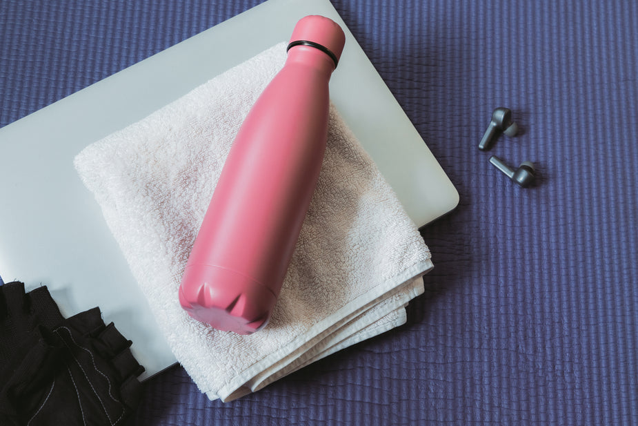 Pink water bottle on towel and purple mat