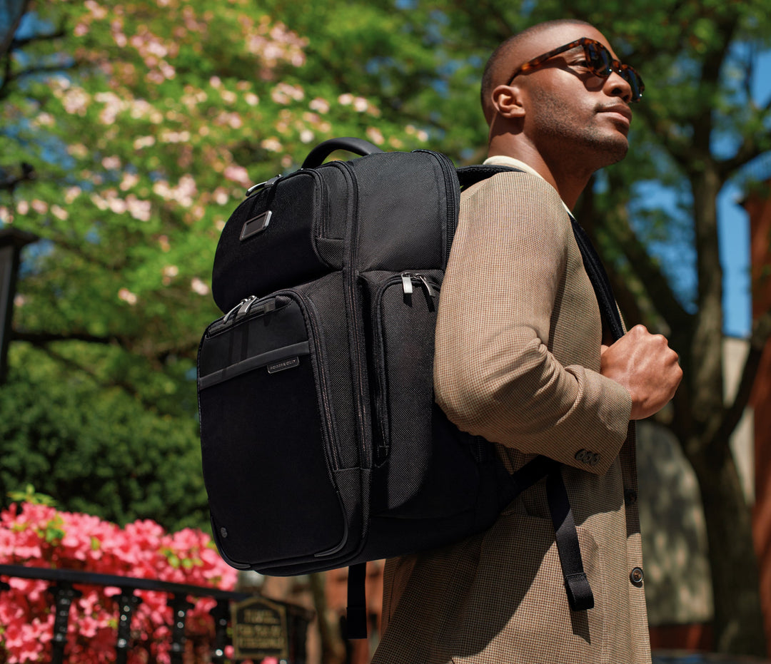 man traveling with briggs and riley black backpack on sunny day