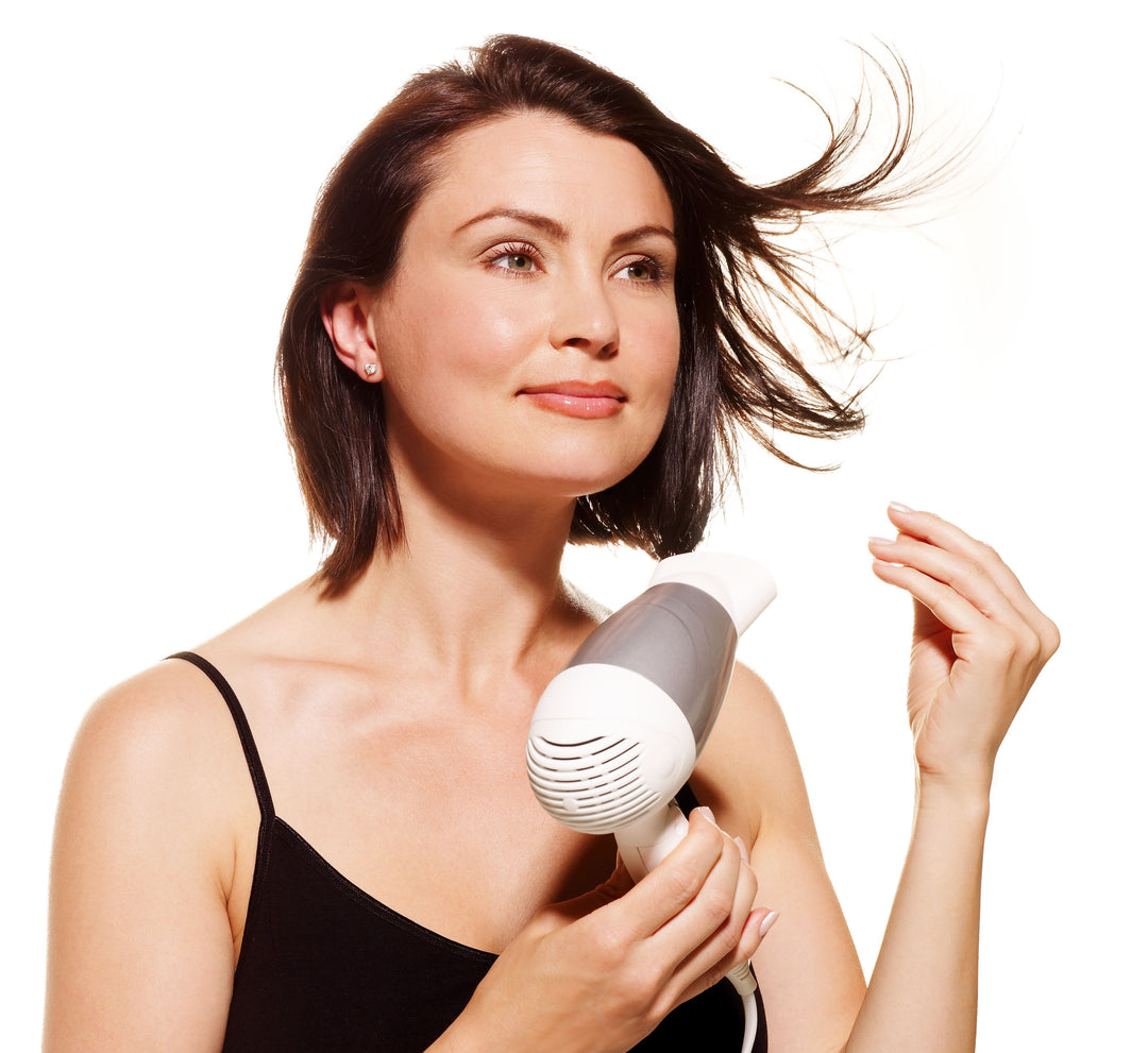 woman blow dries hair with travel hair dryer