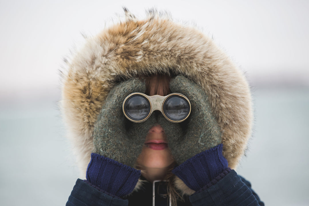 woman wearing binoculars and fur parka