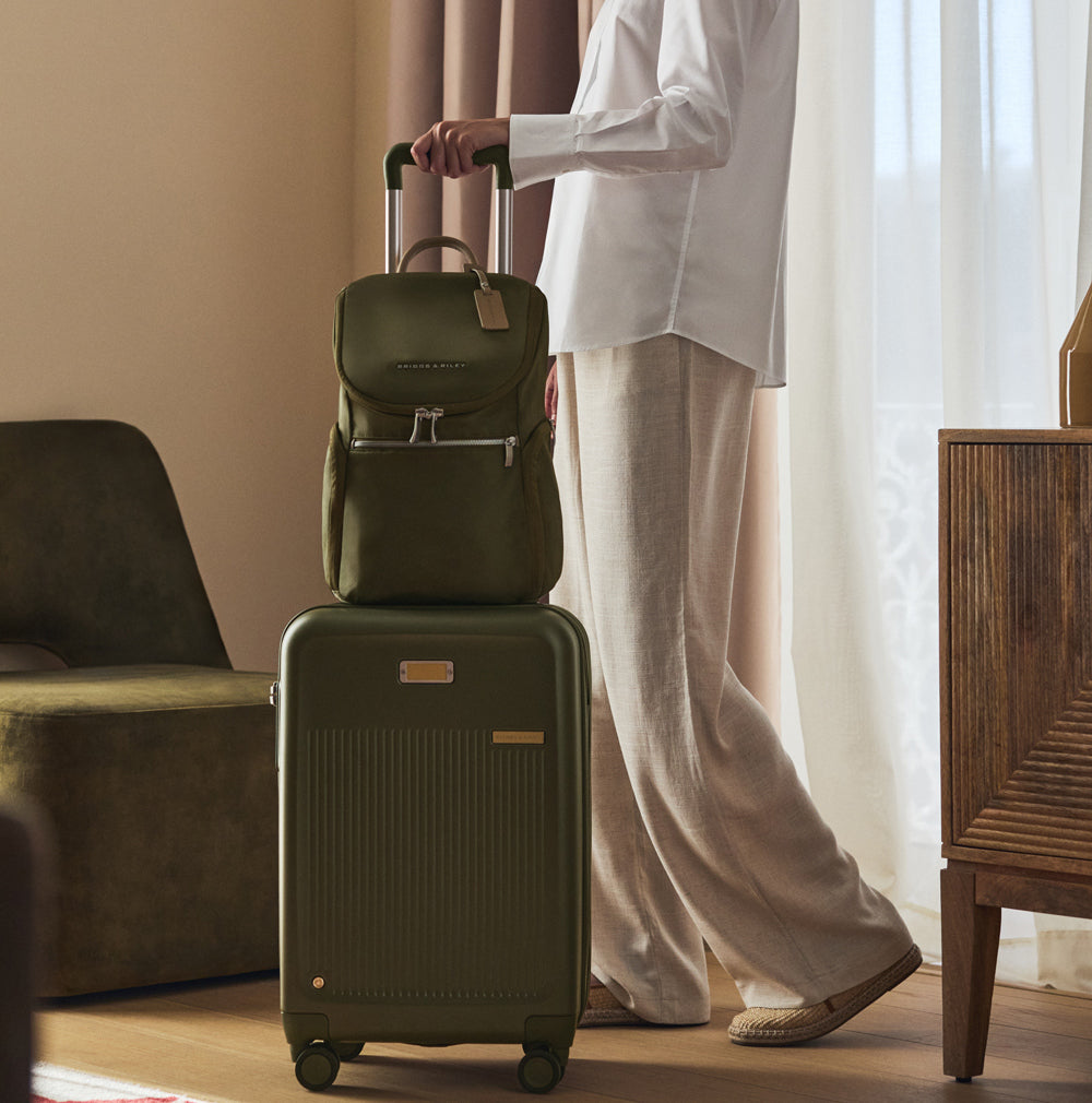 woman checking out of hotel with green carry on luggage