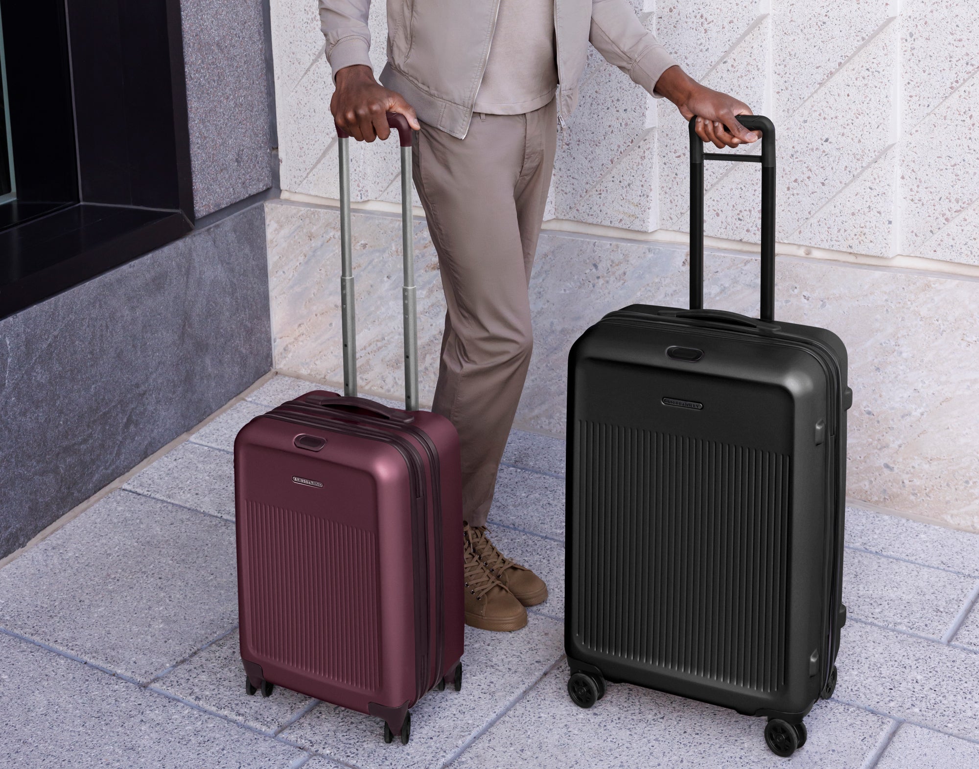 man holding two wheeled hardside suitcases