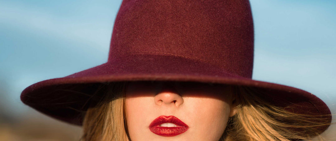 woman wearing burgundy travel hat and red lipstick