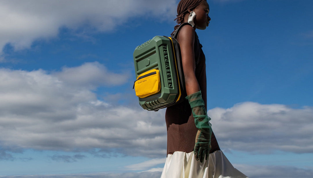 woman walks on beach with hardside Delsey backpack in color green