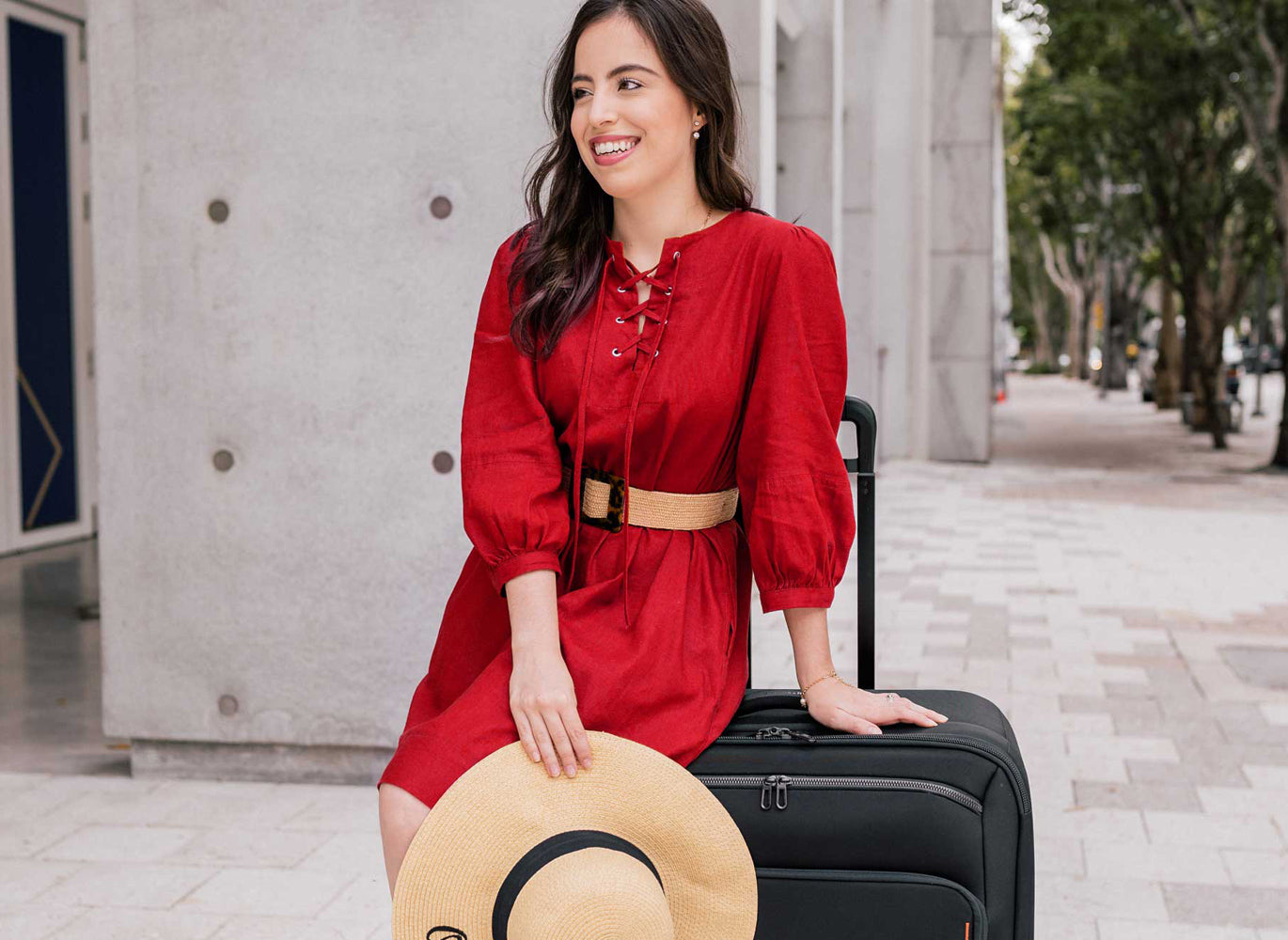 Woman in red dress sitting on Briggs and Riley suitcase palo alto ca