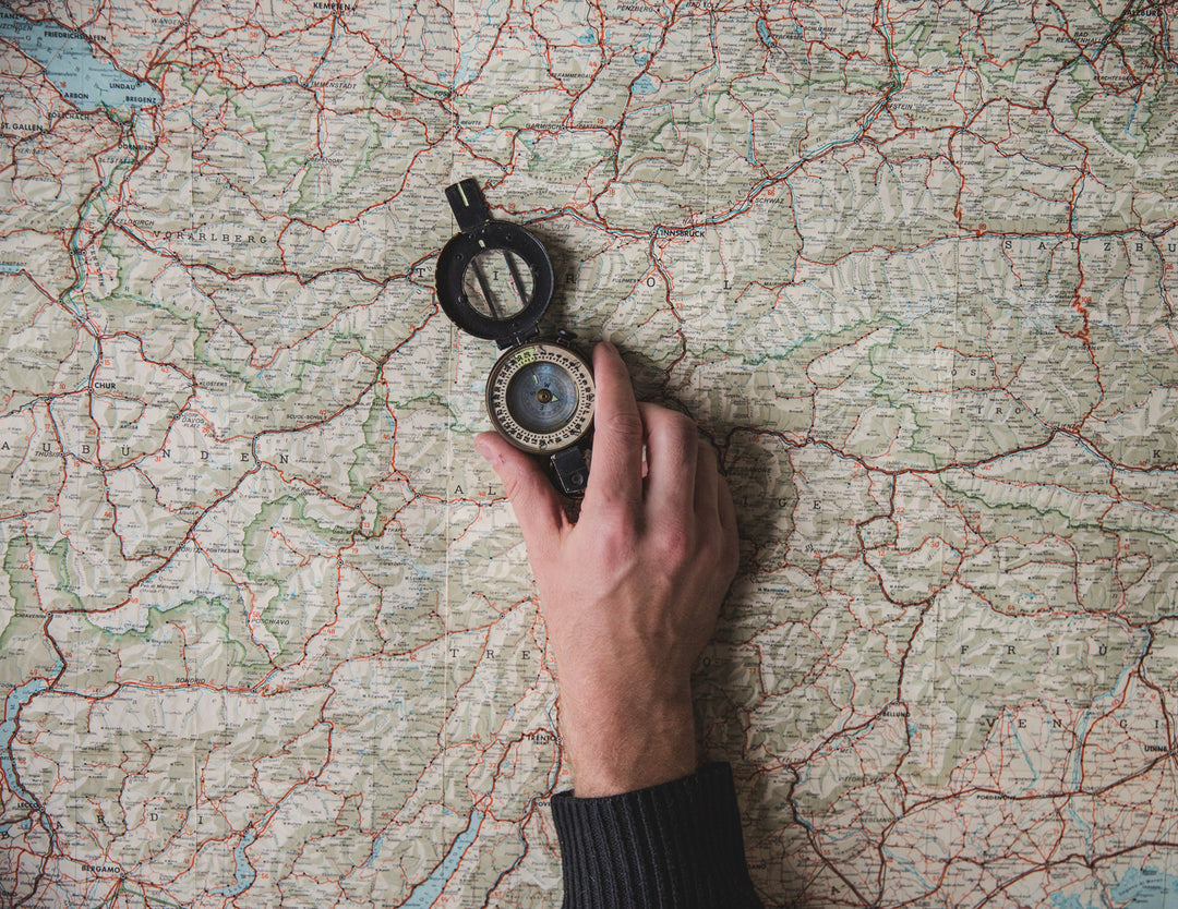 Man holding Lewis N Clark compass travel accessory against map