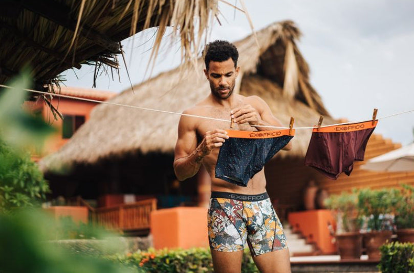 man hanging ex officio underwear to dry outside hut