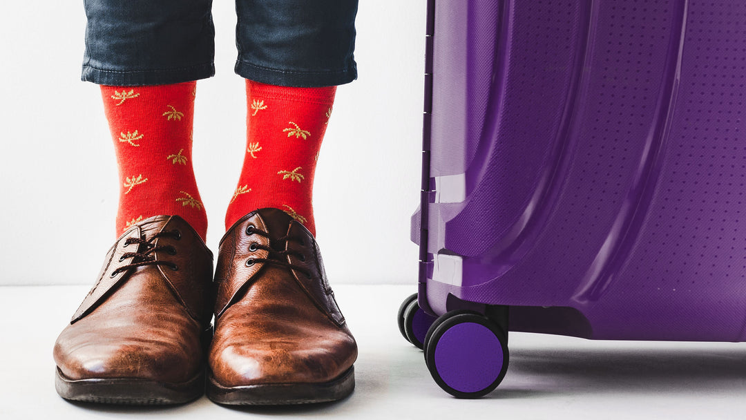 man with red travel socks and purple suitcase