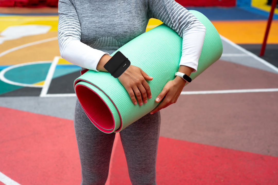 Woman wears Pacsafe wrist wallet while carrying yoga mat