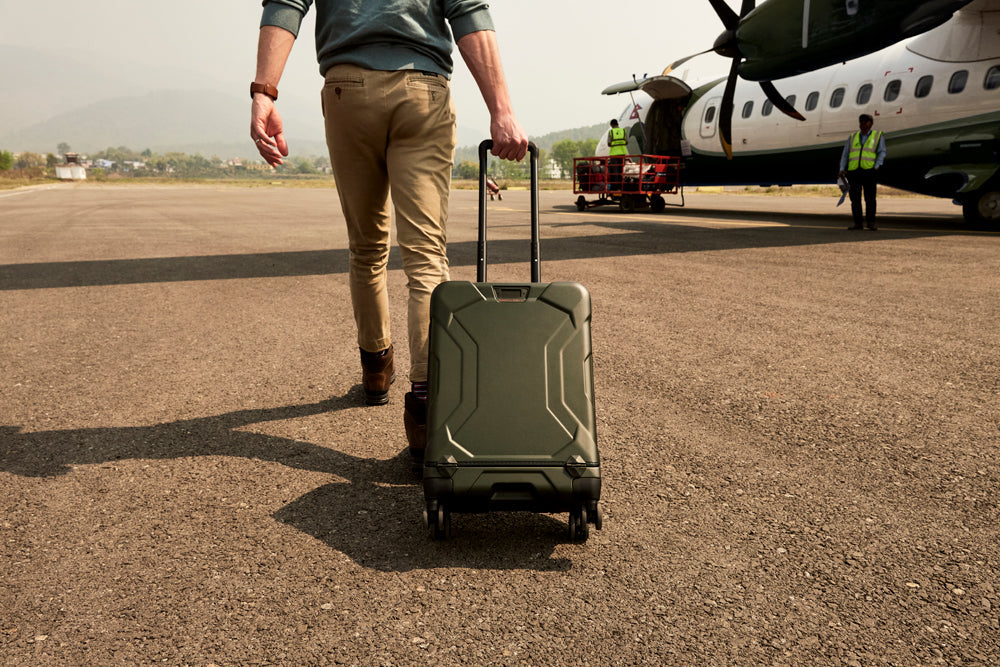 Man getting on airplane with green hardside briggs and riley torq luggage