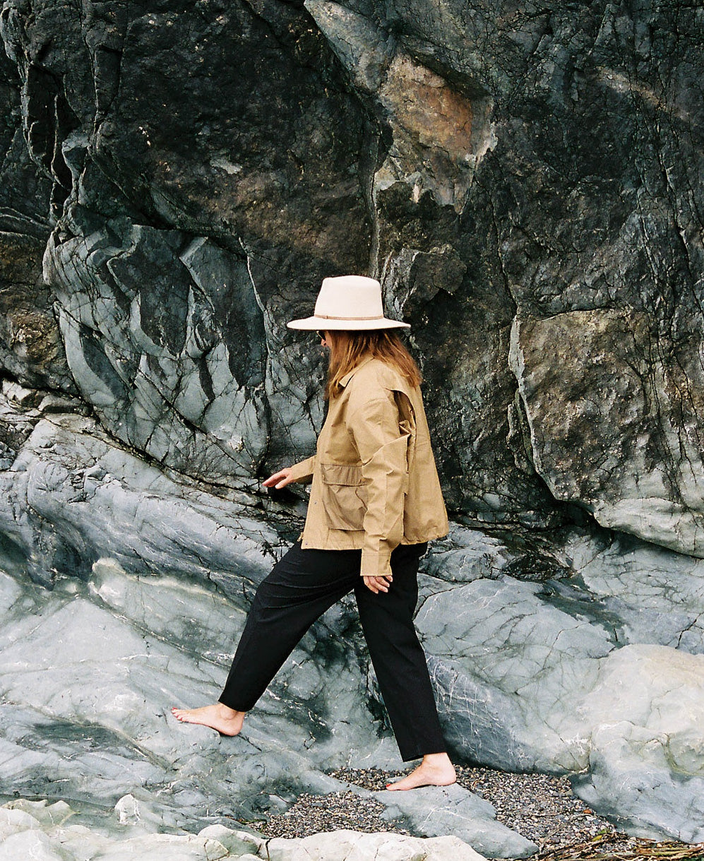 Woman walking barefoot on travel adventure wearing a Tilley Travel Hat