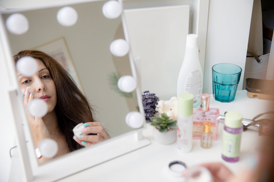 woman putting on travel lotion in hotel mirror