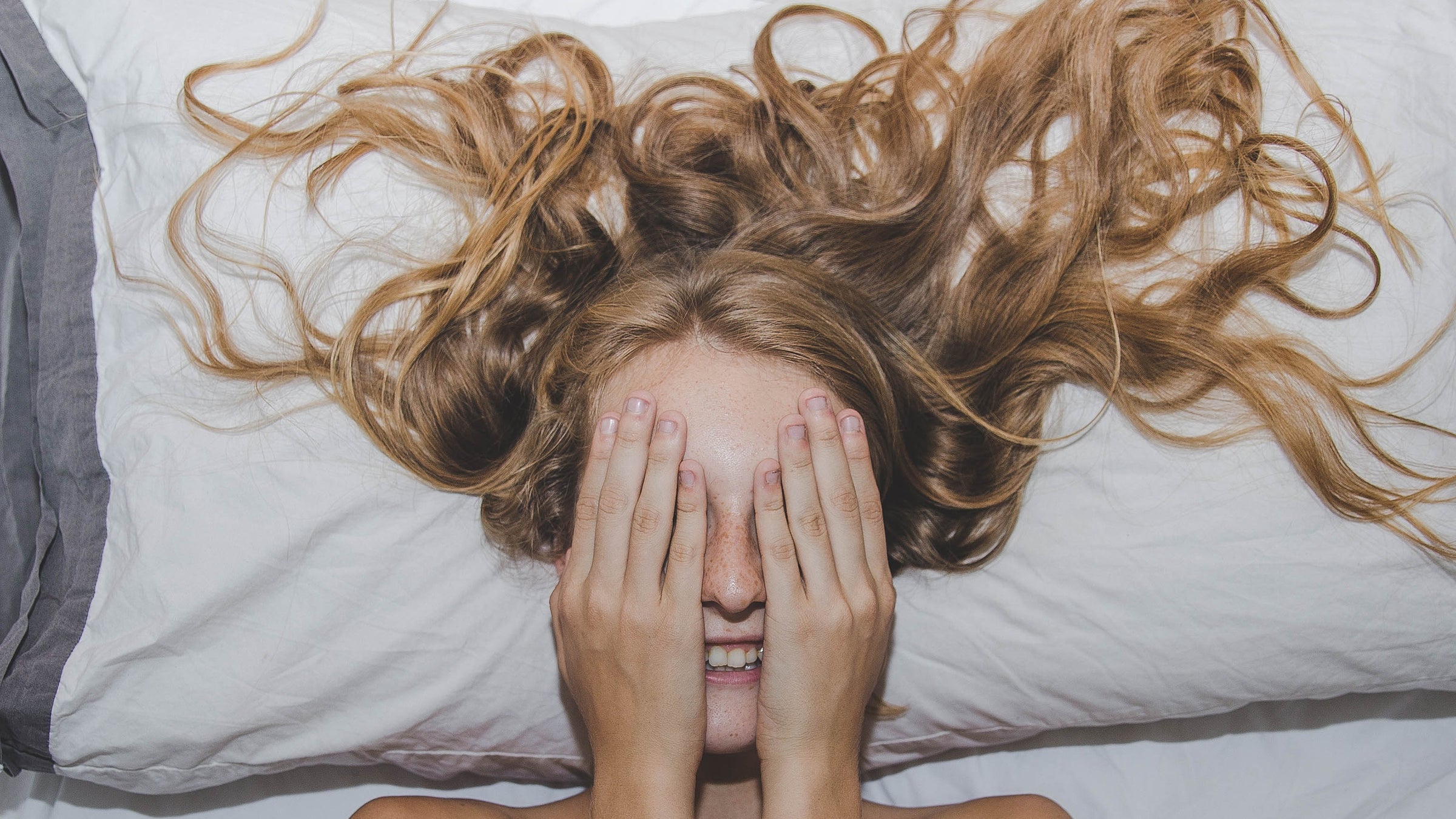 woman sleepin in hotel room with travel pillow