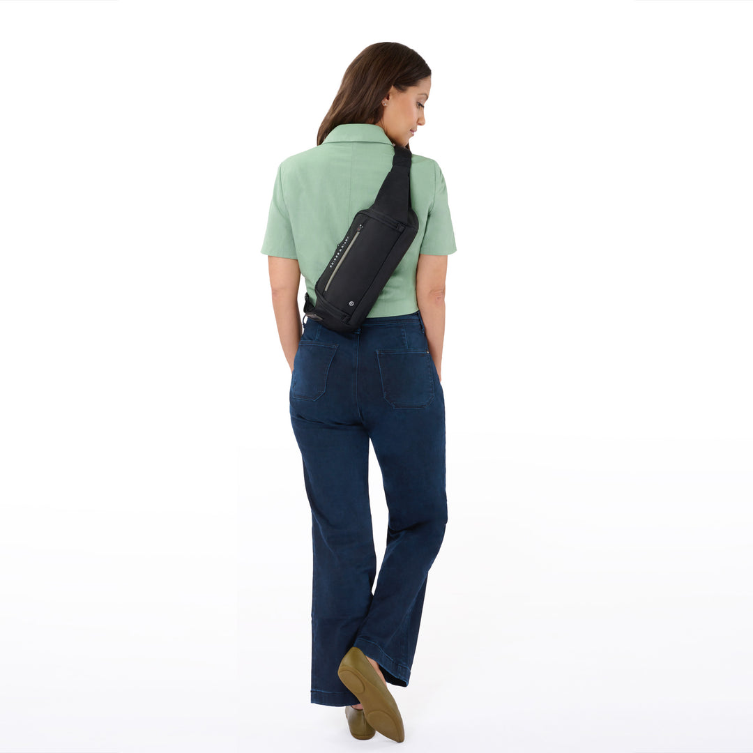 Woman in green shirt models HTA sling bag worn on back