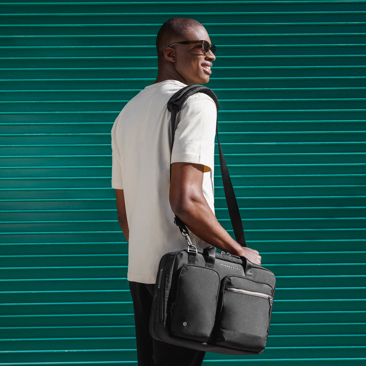 Man standing with briefcase against teal wall