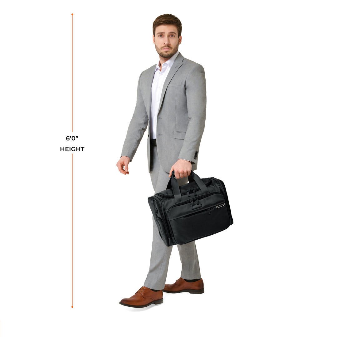 Six foot tall model carries Briggs & Riley Baseline Underseat Duffle from top handle