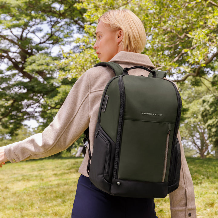 Woman walks through park with green medium widemouth backpack