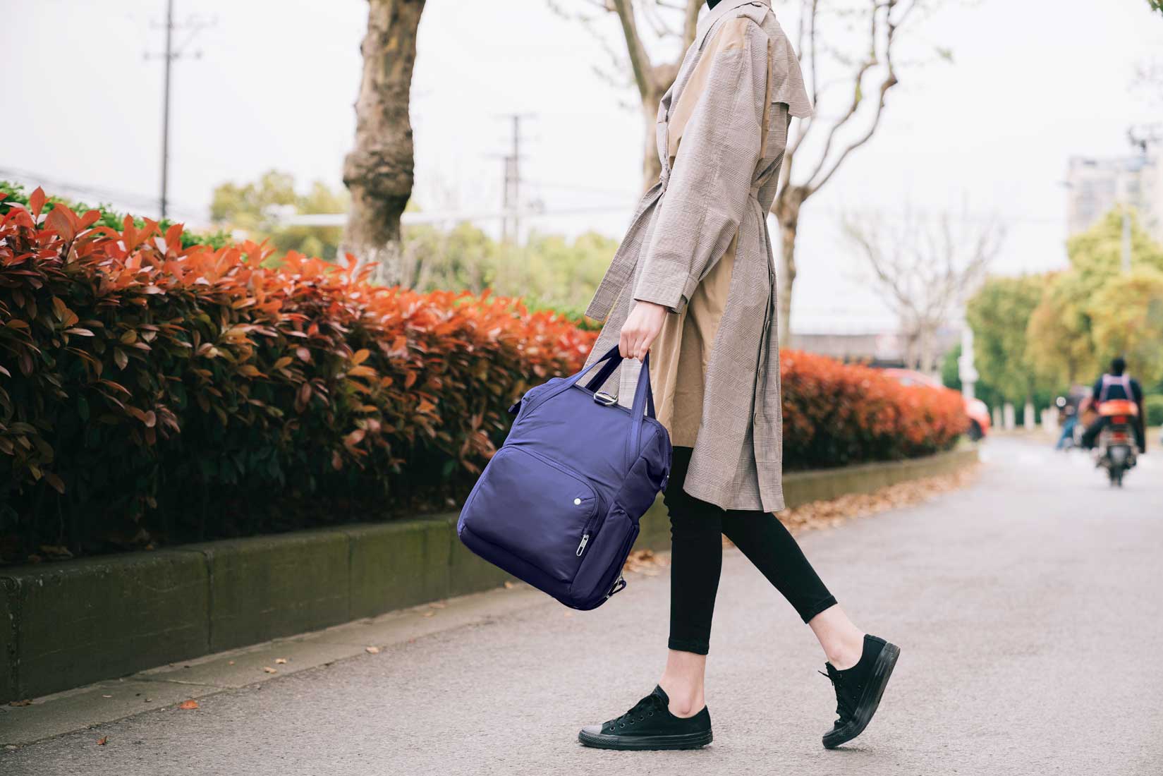 woman walking downtown with purple pacsafe anti theft bag