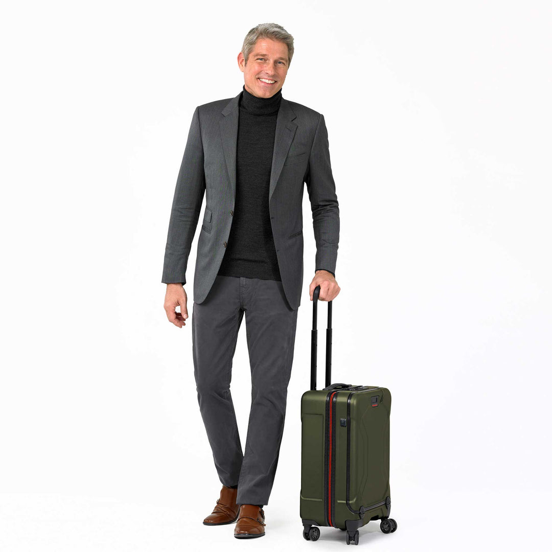 Man in suit rolling hunter green torq domestic carry on suitcase