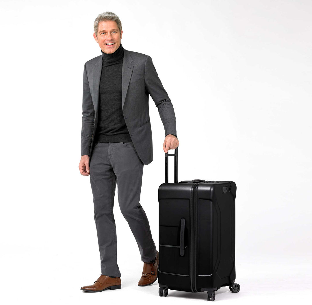 Black Briggs & Riley Torq Medium Hardside Trunk Spinner with male model in suit