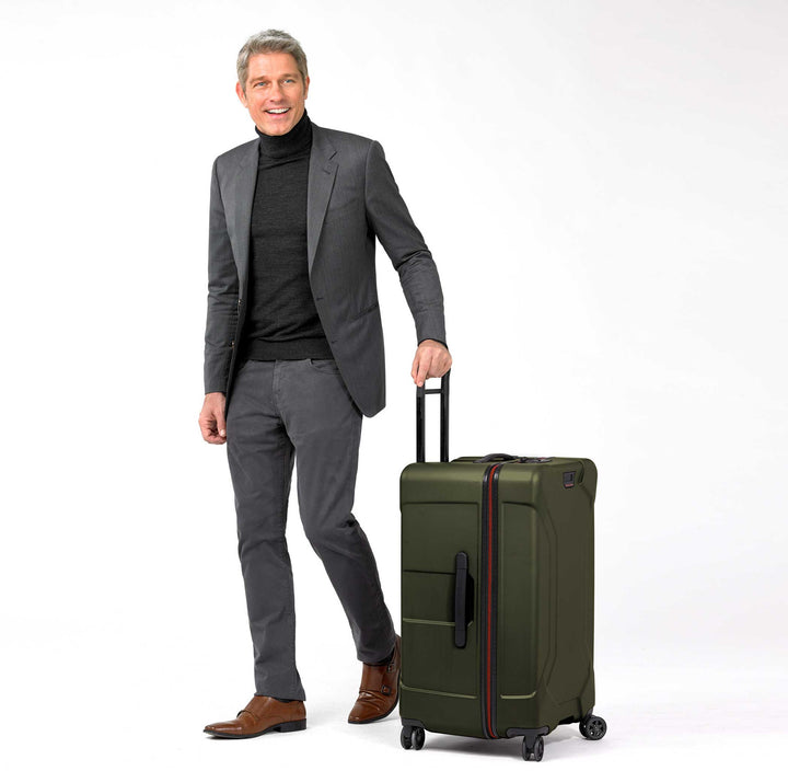 Hunter Green Briggs & Riley Torq Medium Hardside Trunk Spinner with male model in suite