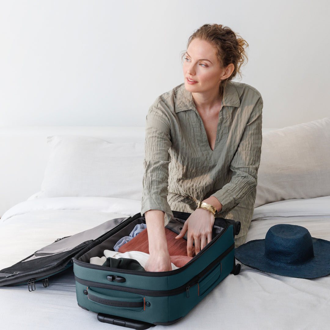 Woman packs her Ocean Blue 22 Inch ZDX Carry On with clothing and Hat