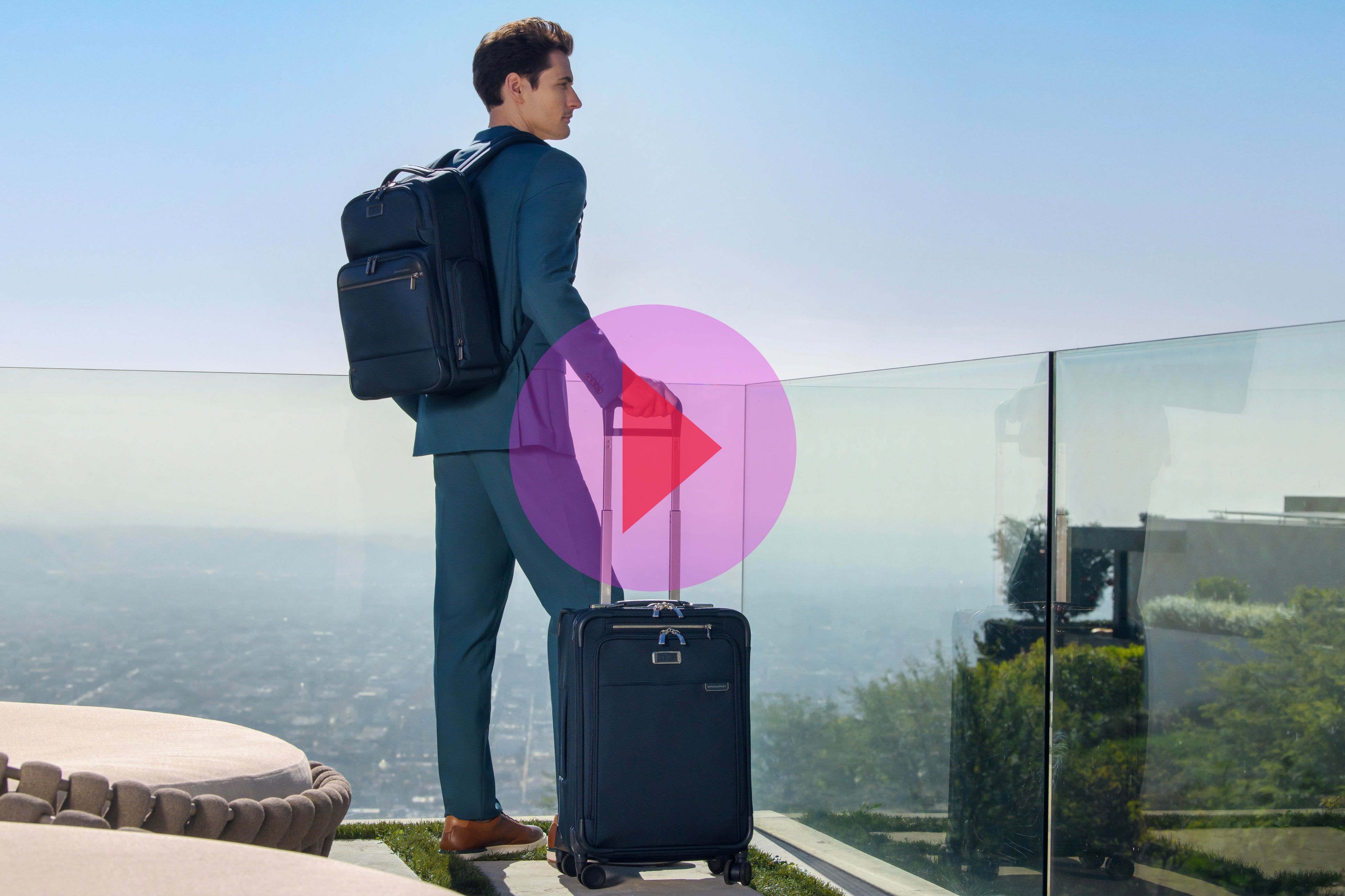 Man stands in blue suit with blue luggage waiting for taxi at hotel