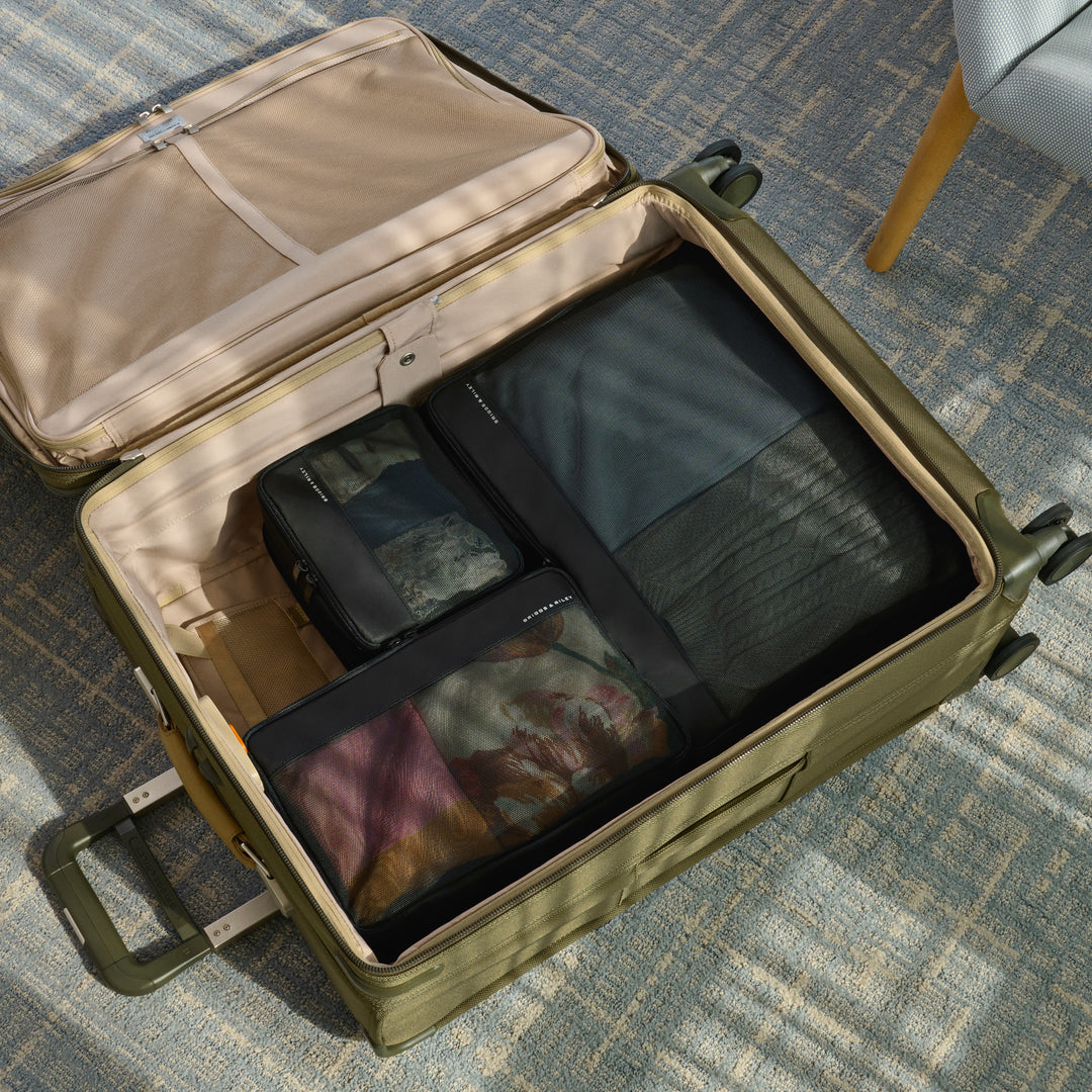 Check In Packing Cube set three piece packed into green suitcase on floor