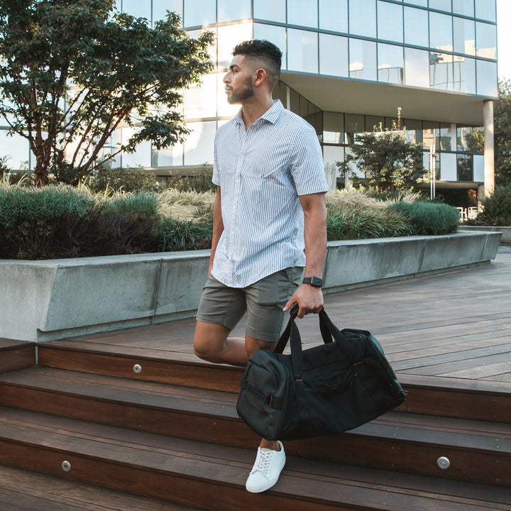 Man leaves the recreation center at sunset holding his black Briggs & Riley ZDX Large Travel Duffle as a gym bag