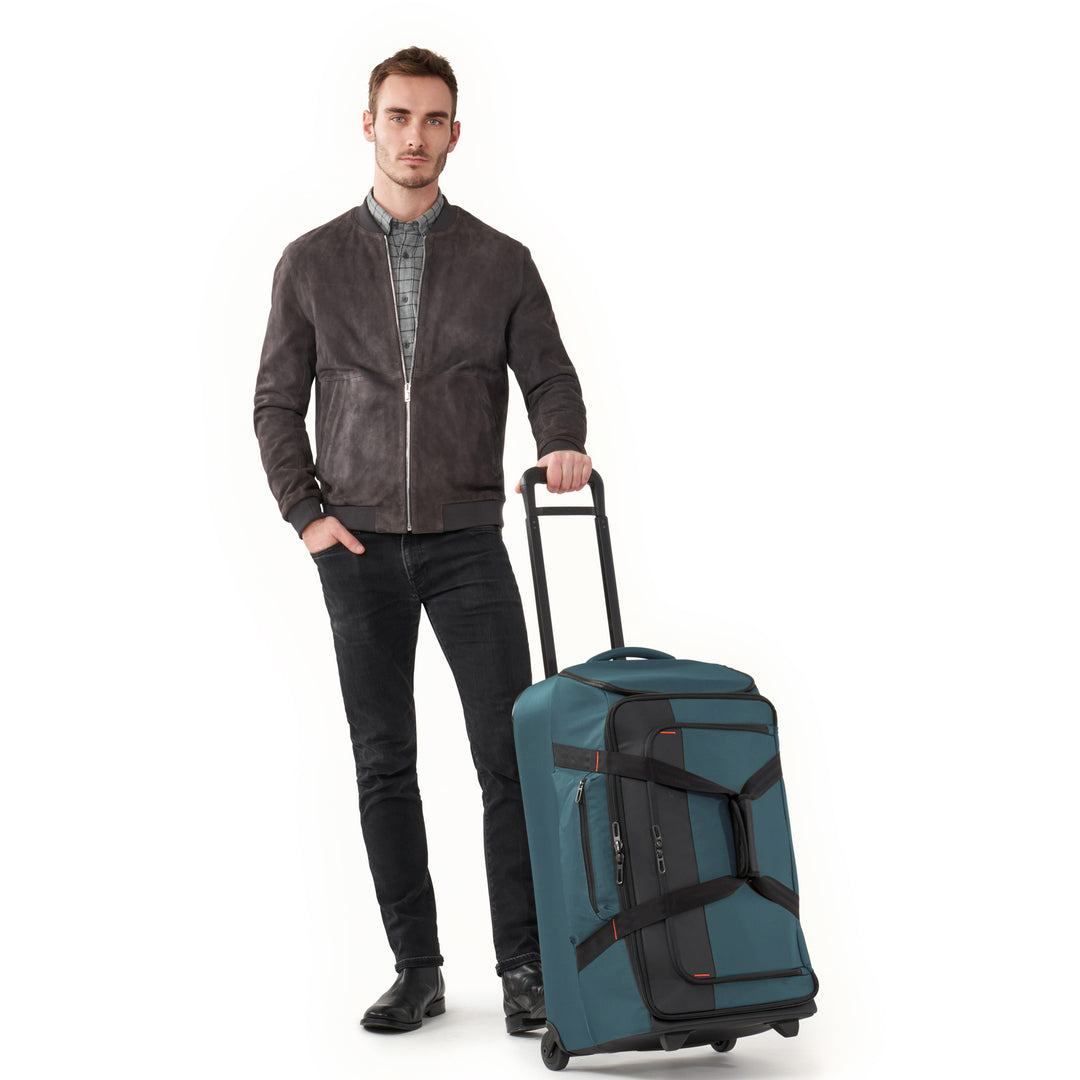 Man Holding Handel of Briggs & Riley ZDX Medium Upright Duffle in color Ocean Blue