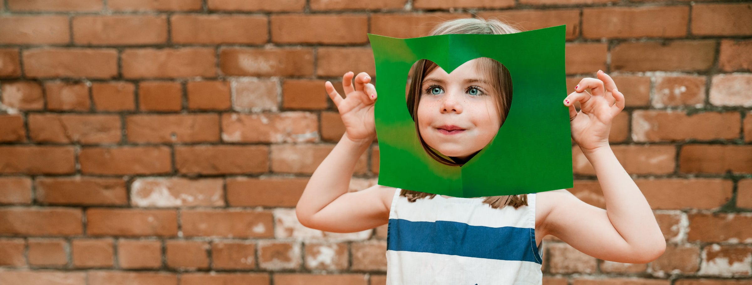 Little Girl Foster Kid puts face through cut out paper heart