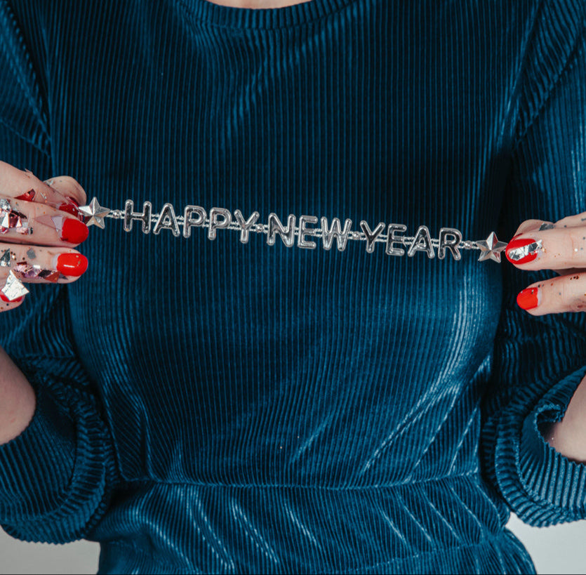 woman with red nail polish holding happy new year ribbon