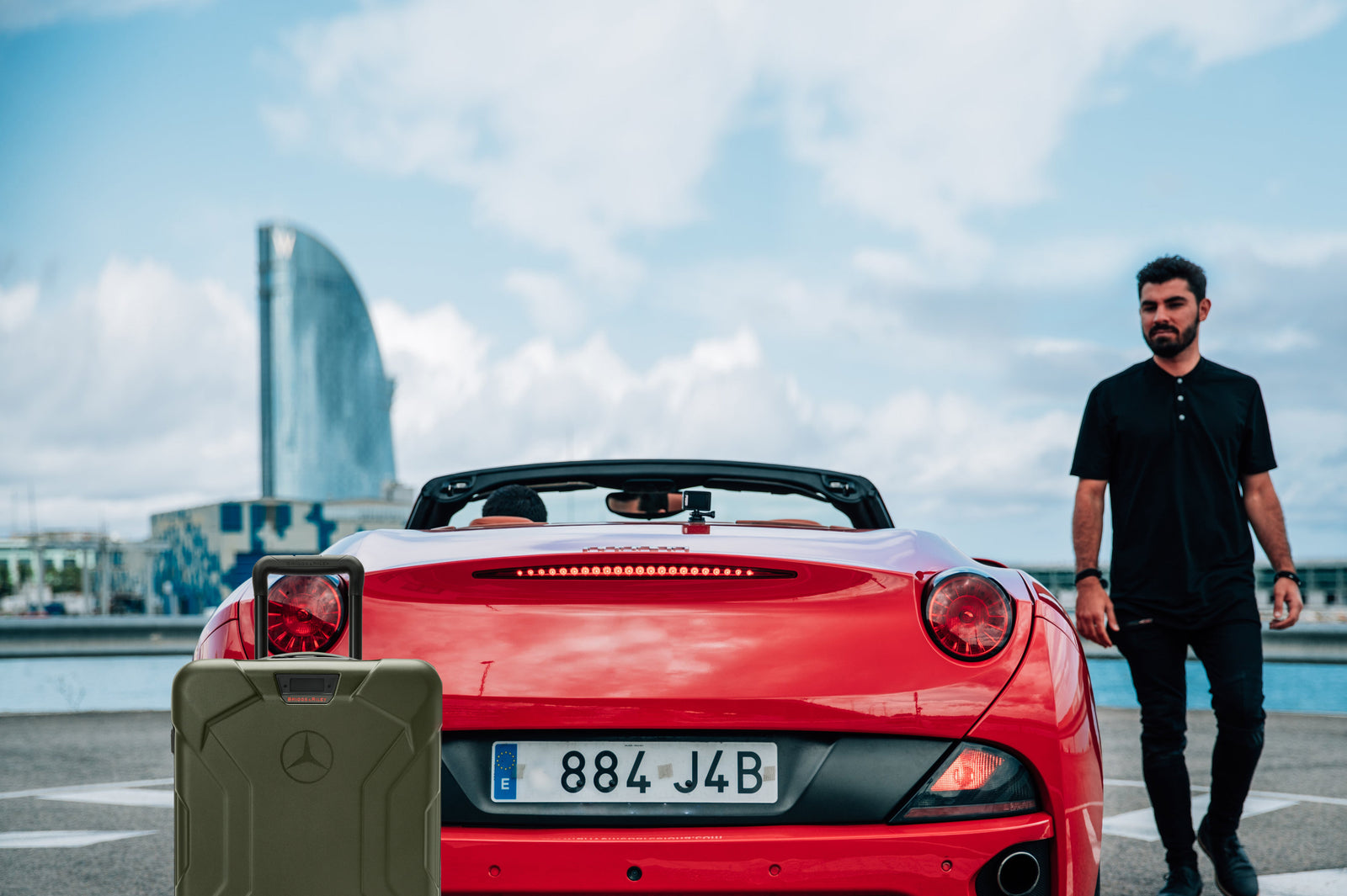 Man puts torq luggage into red fancy sports car