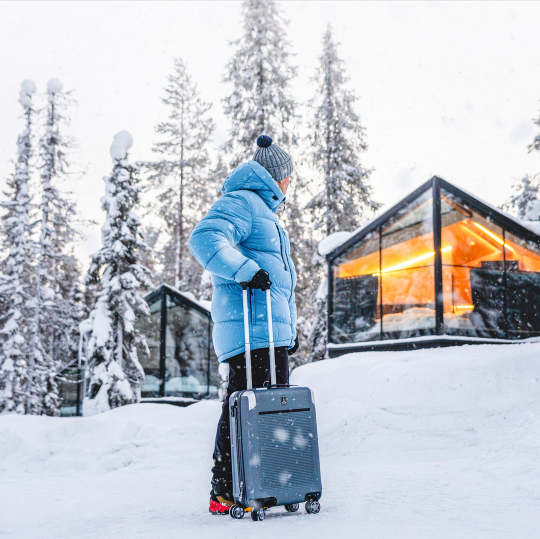 Checking into snowy cabin with blue Travelpro luggage