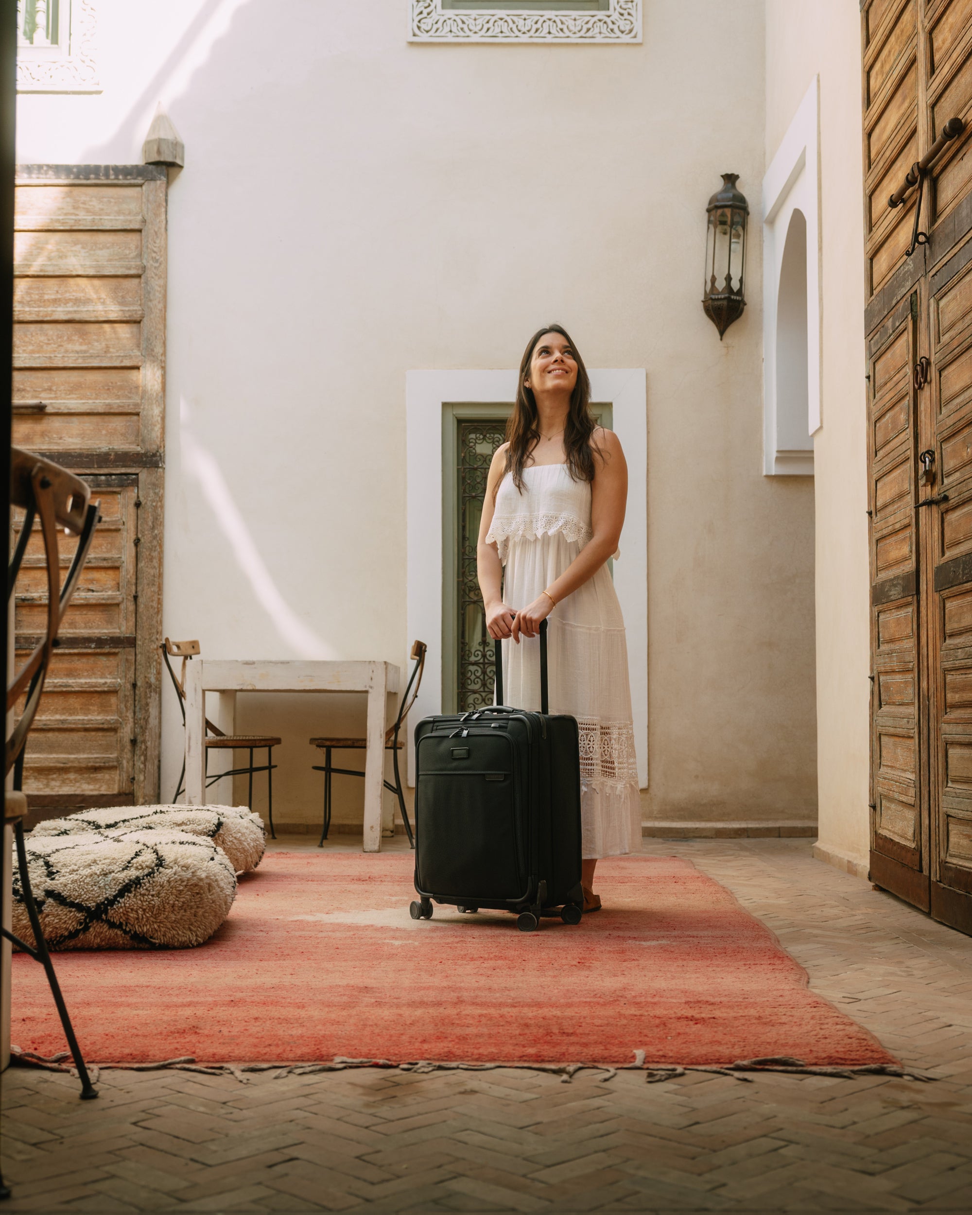 woman standing in air bnb with briggs and riley suitcase